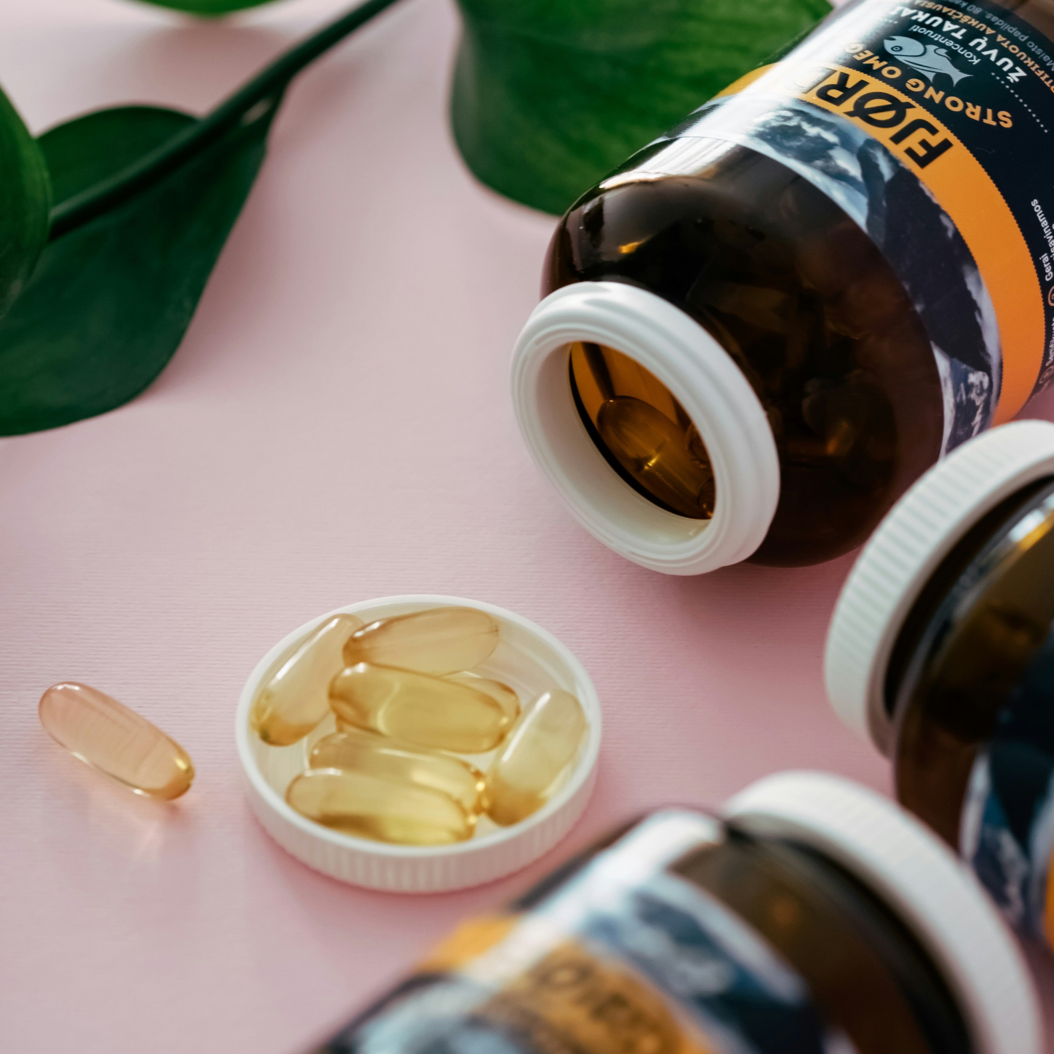 Essential Fatty Acids softgel capsules from CanadianVit in brown bottle with leaves on a pink background.