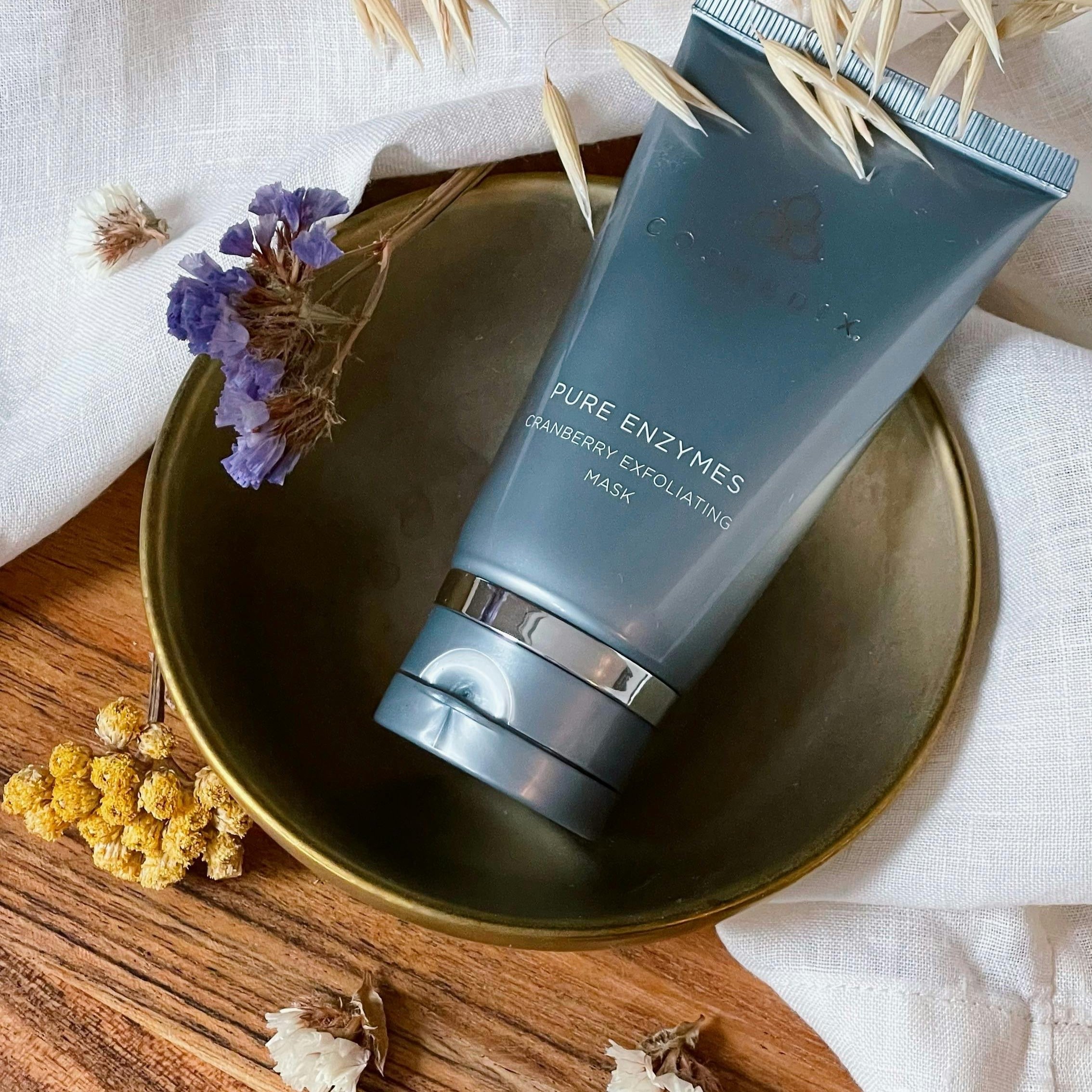 Pure Enzymes cranberry exfoliating mask in a decorative bowl, enhancing skin with natural ingredients.