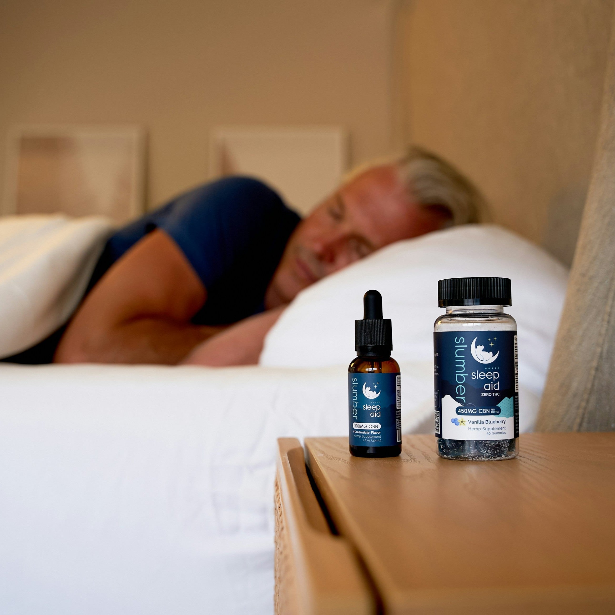 Sleep Supplements on bedside table with a man sleeping peacefully in the background.