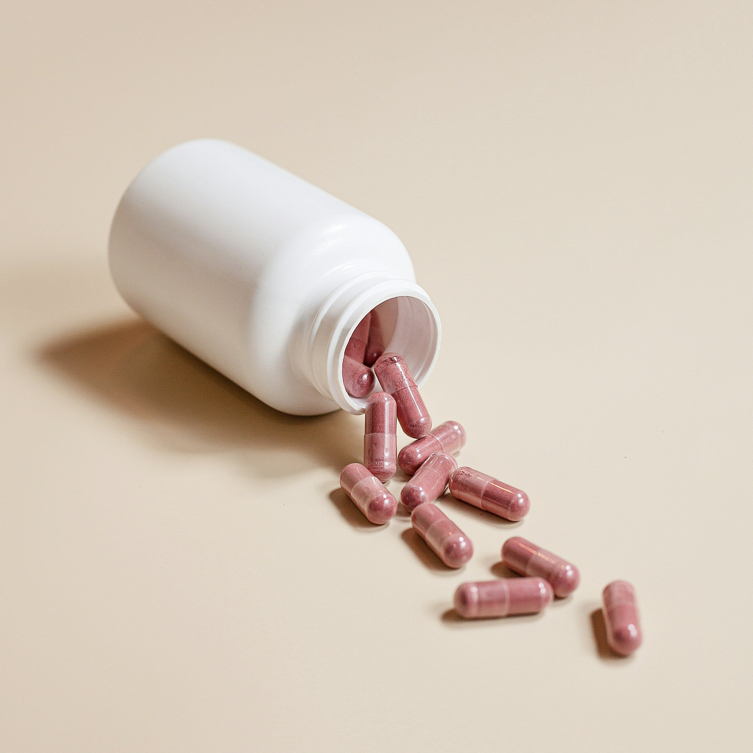 Fiber Supplements for Digestive Health in pink capsules spilling from a white bottle.