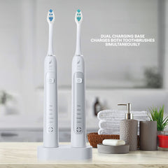 Two white Acteh Sonic Toothbrush handles with charging base