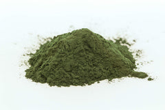 Spoon with spirulina powder next to a glass illustrating usage