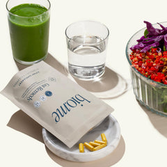 Bio.me Biome Gut Remedy capsules with water illustrating easy daily dosing ritual.