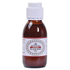 Glass dropper applying black seed oil from the bottle