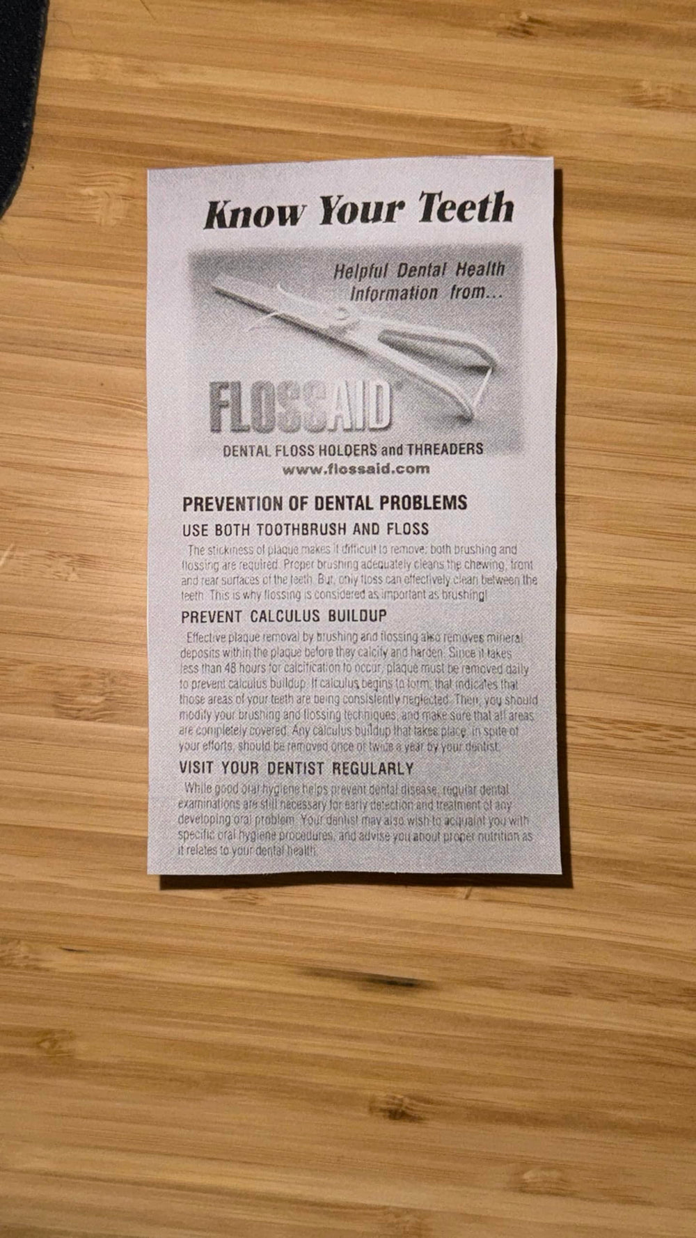 Close-up of FLOSSAID floss holder showing angled head and colors