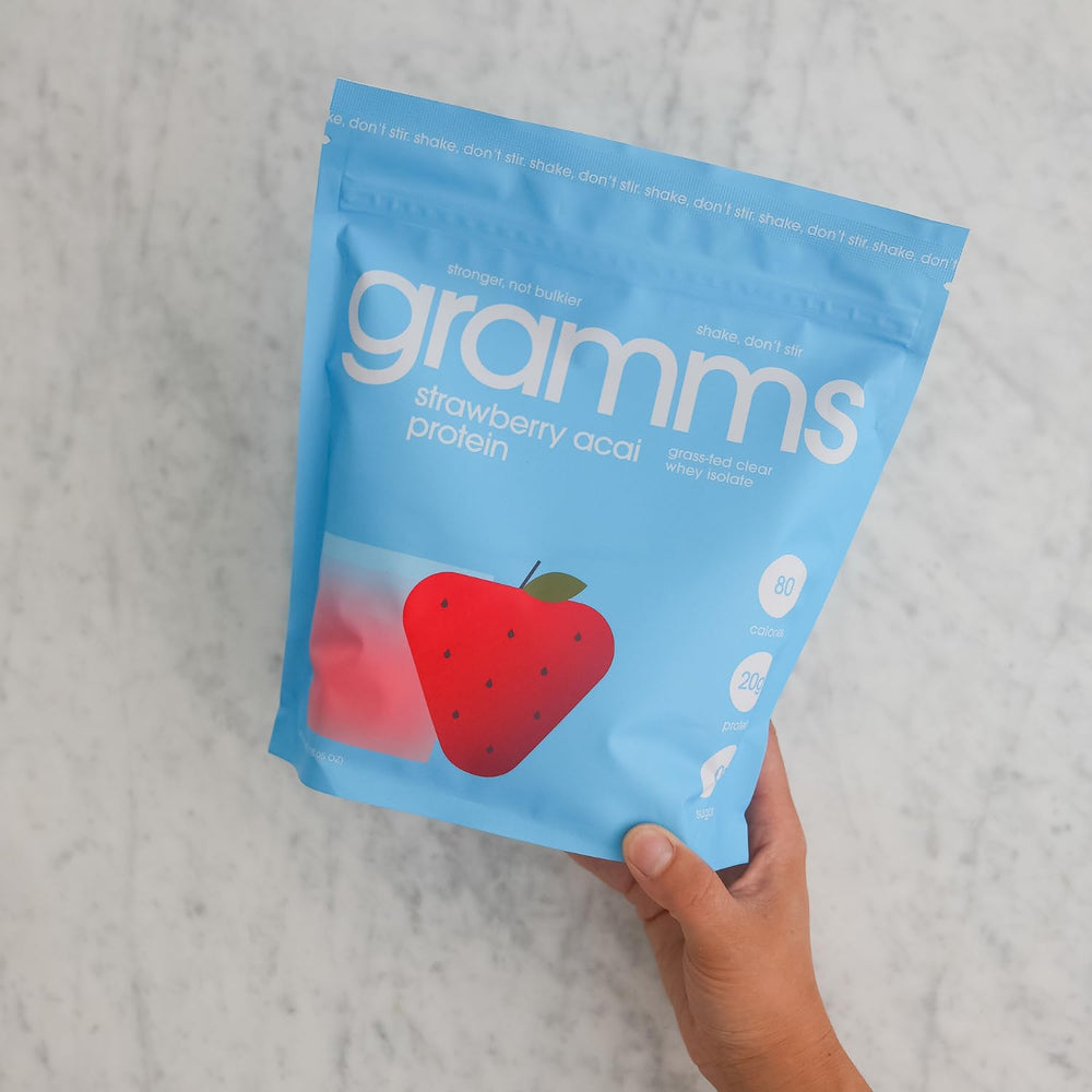 Fruity strawberry acai taste of GRAMMS Clear Protein Powder dissolving in water