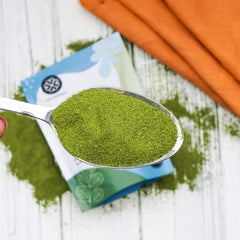 Moringa powder being scooped with a teaspoon