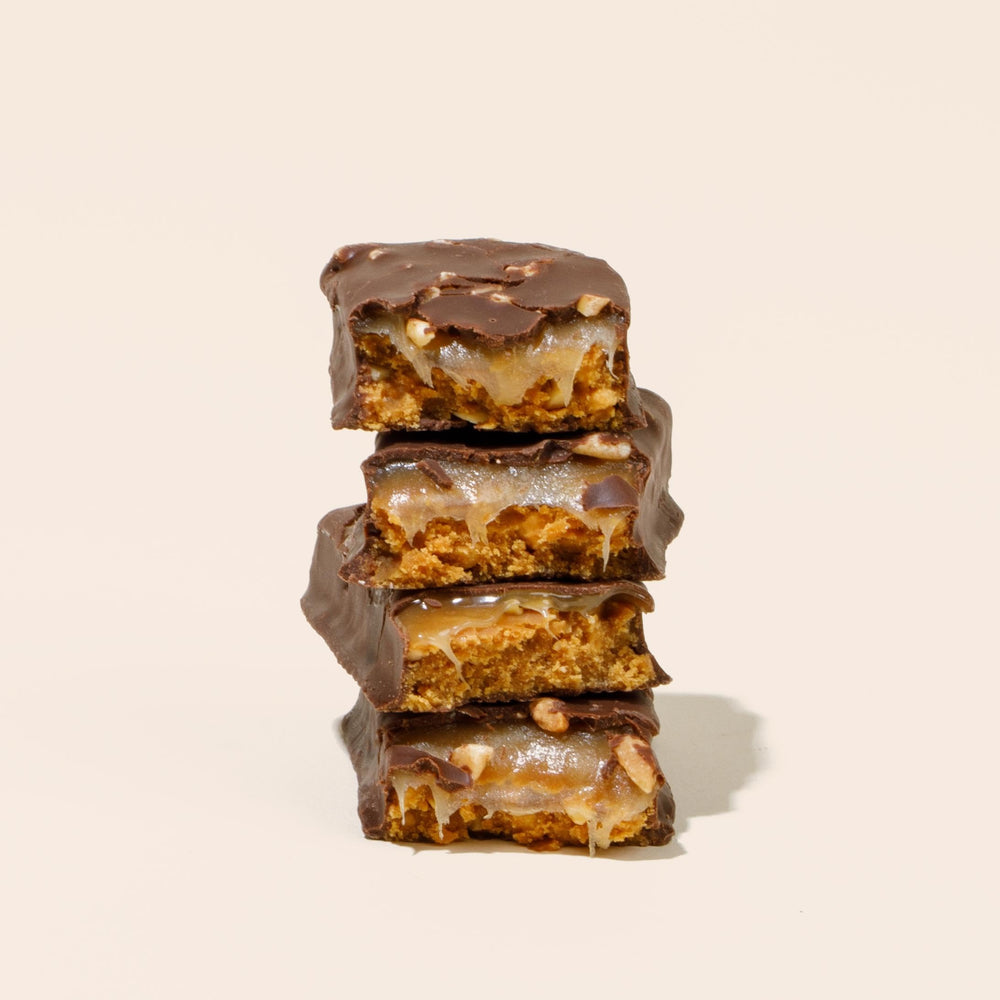 No Cow chocolate caramel peanut bar being grabbed in a gym bag for post-workout fuel.