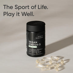 A person taking Sports Research vegan omega-3 capsule with a meal