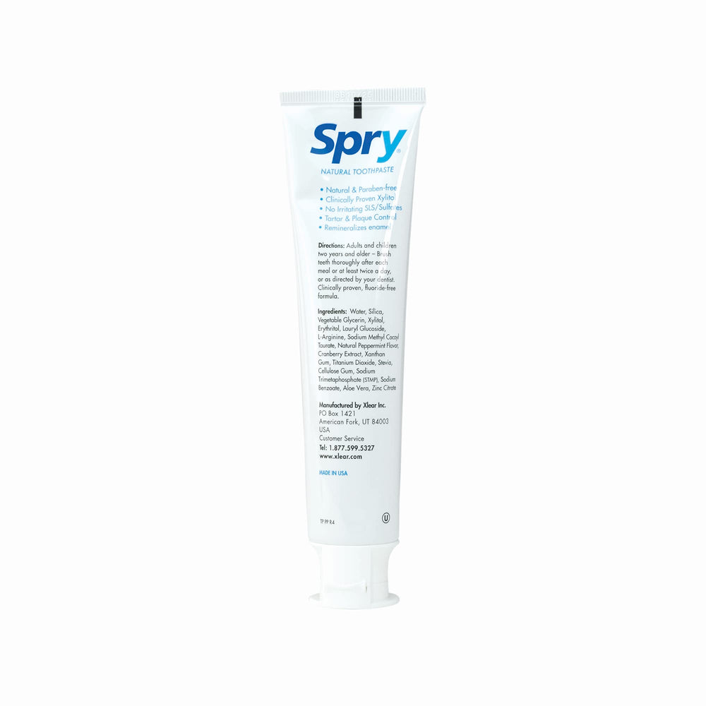 Toothpaste tube lying next to peppermint leaves