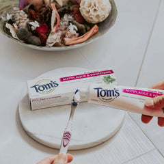 Toothbrush and Tom's of Maine toothpaste on a bathroom counter