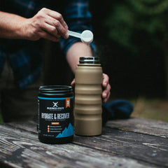 Wilderness Athlete Hydrate and Recover glass blue-raspberry displays a ready-to-drink hydration beverage after workouts.