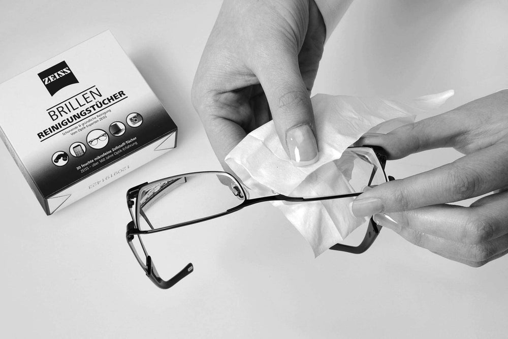 Hands cleaning eyeglasses with Zeiss lens wipes