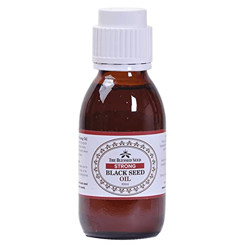 Glass dropper applying black seed oil from the bottle