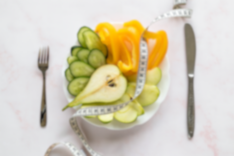 Fruit salad on a plate with a measuring tape, symbolizing healthy eating and weight management.