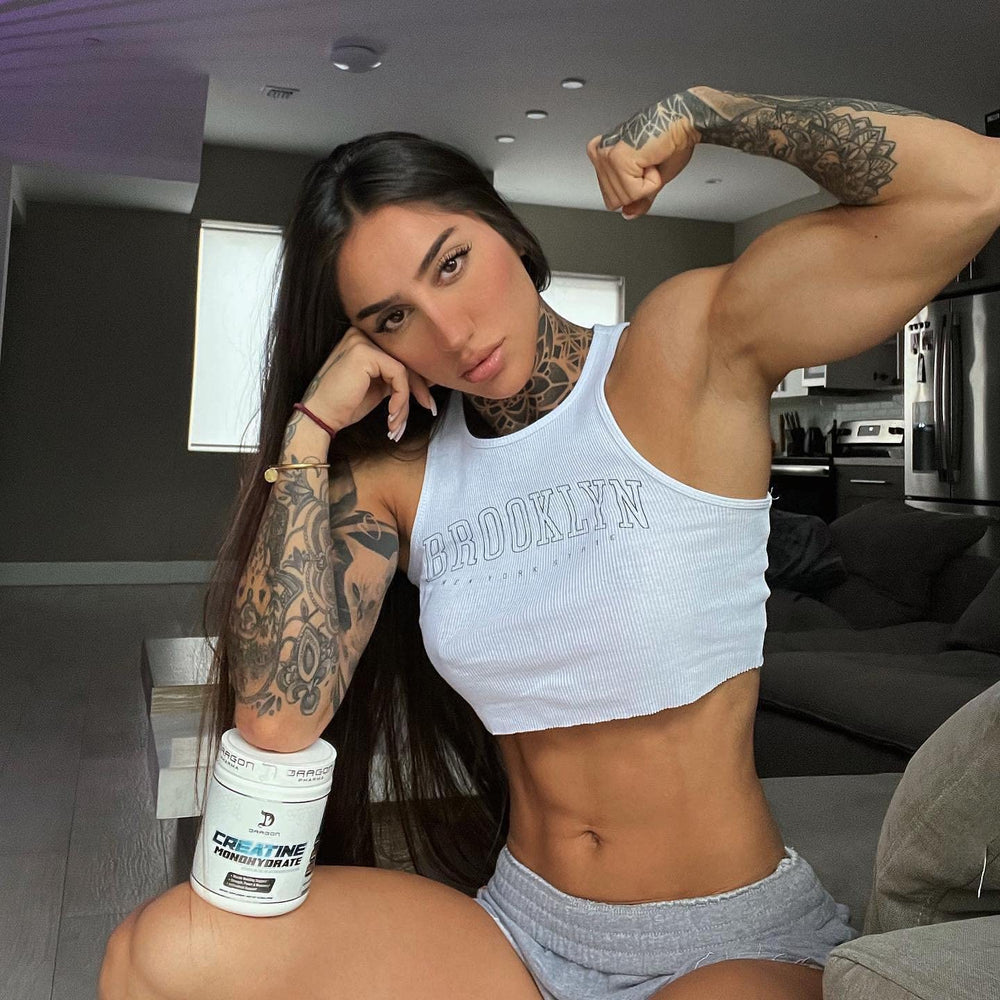 Creatine powder with scoop beside glass of water