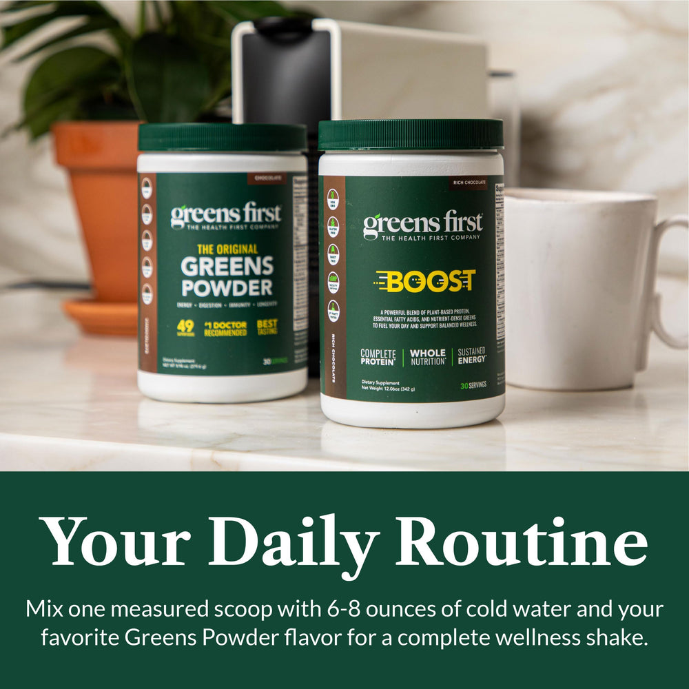 Greens First Boost shake next to fresh fruit on a kitchen counter.