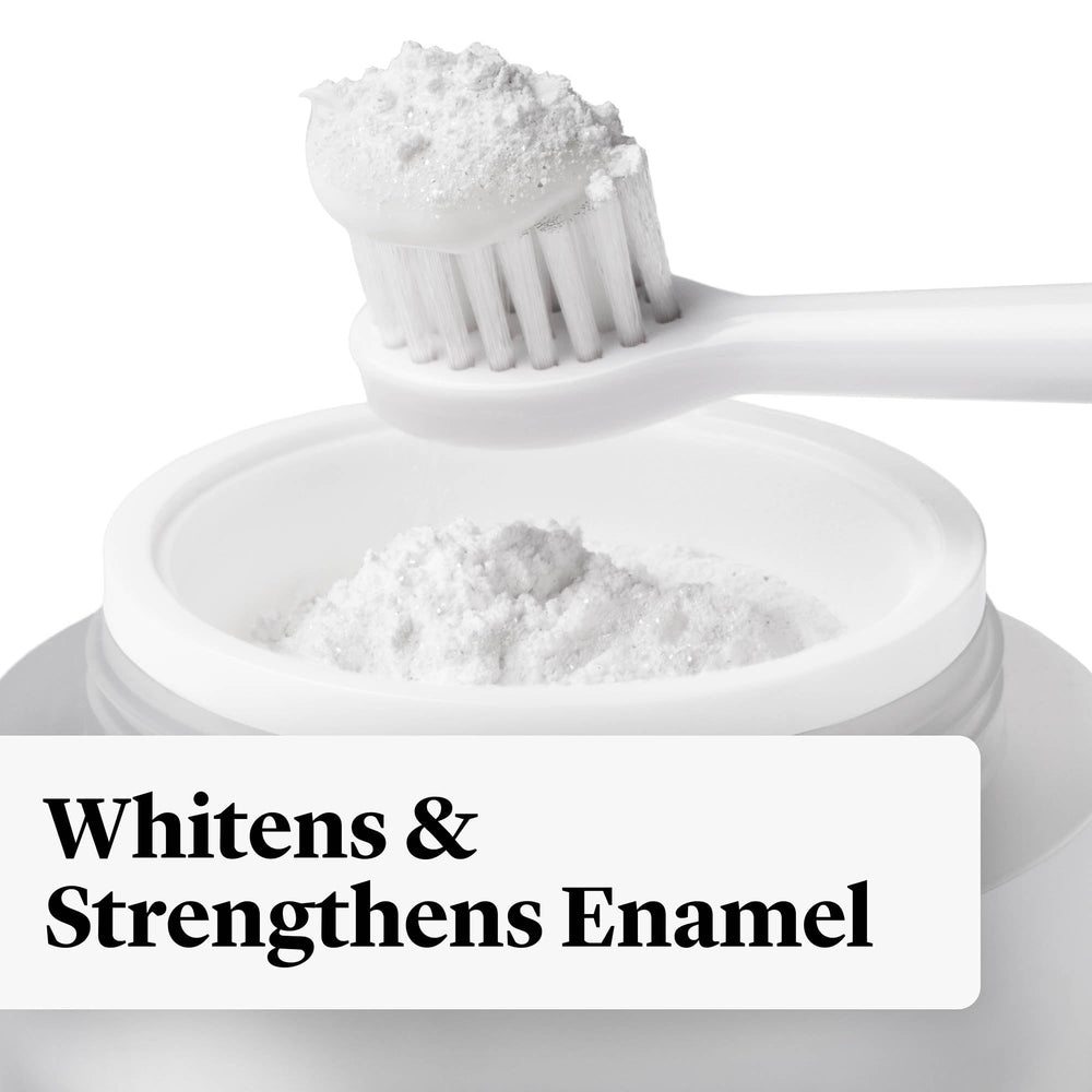 Toothbrush dipped into whitening powder over toothpaste