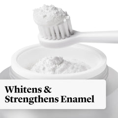 Toothbrush dipped into whitening powder over toothpaste