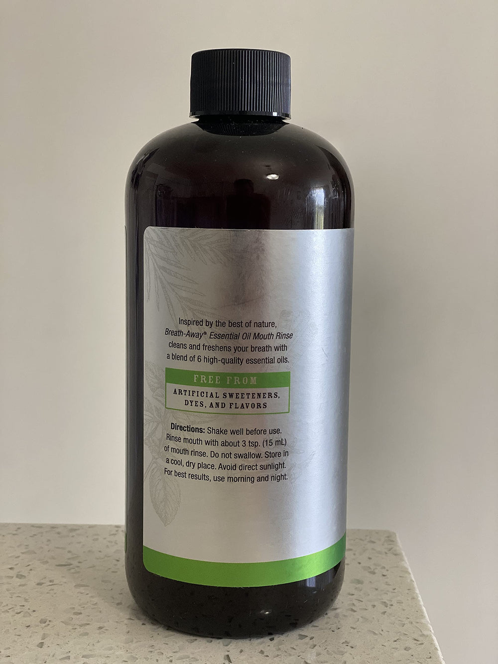 Pouring Melaleuca Breath-Away Mouth Rinse into a glass with fresh mint leaves