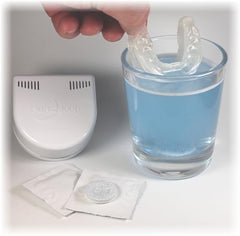Minty blue effervescent tablet next to a glass of water